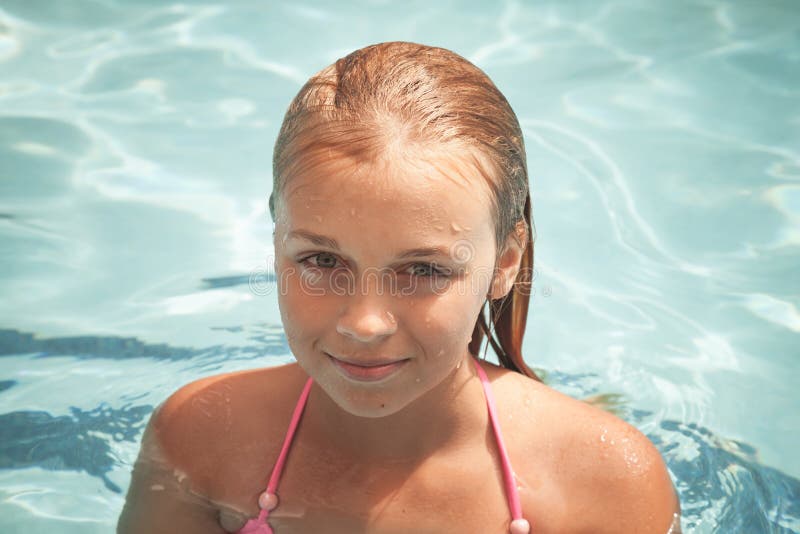 Beautiful smiling blond girl swims in a pool