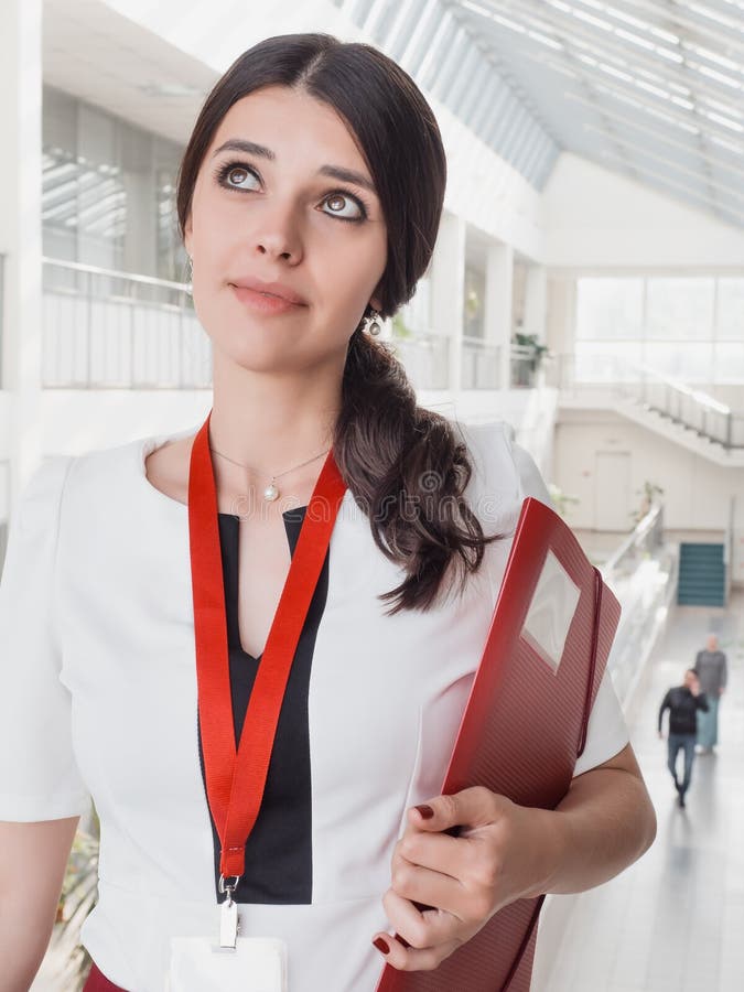 Beautiful Smiling Businesswoman Standing Against White Offices Background. Portrait of Business Woman With a Folder in Her Hands royalty free stock images Beautiful Smiling Businesswoman Standing Against White Offices Background. Portrait of Business Woman With a Folder in Her Hands royalty free stock images