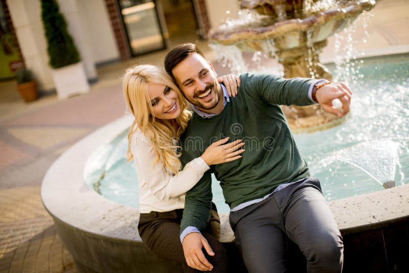 Beautiful smiling love couple sitting by the fountain on a sunny day royalty free stock photos Beautiful smiling love couple sitting by the fountain on a sunny day royalty free stock photos