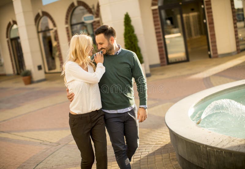 Beautiful smiling love couple walking by the fountain on a sunny day stock photo