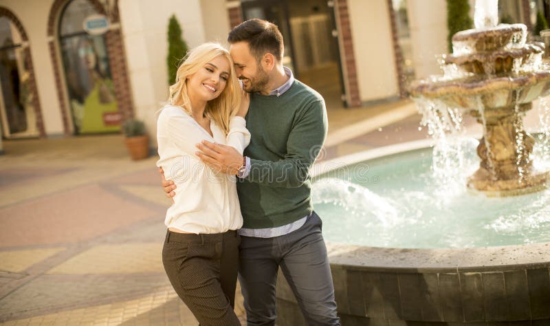 Beautiful smiling love couple walking by the fountain on a sunny day royalty free stock image