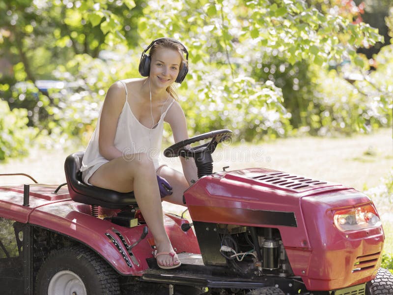 Beautiful smiling teenage girl cutting the lawn