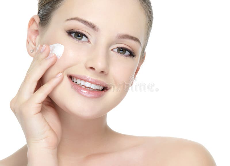 Beautiful smiling woman applying cream on cheek