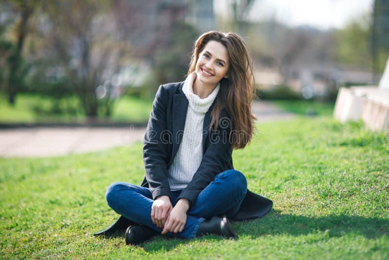 Beautiful smiling woman sitting on a grass outdoor