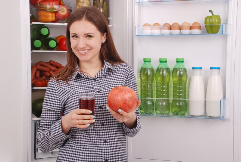 Beautiful smiling young girl holds a glass of pomegranate juice and garnet stock photography Beautiful smiling young girl holds a glass of pomegranate juice and garnet stock photography