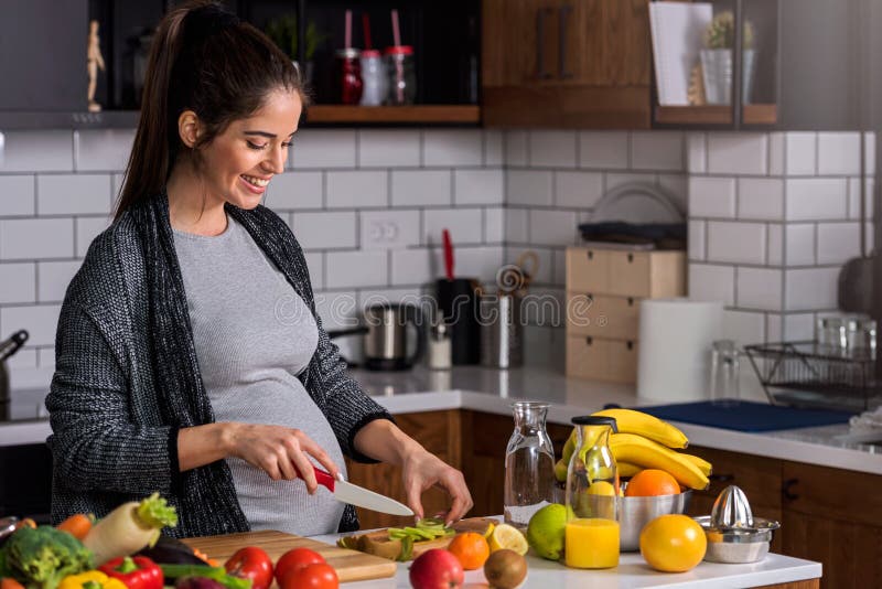 Young pregnant woman preparing healthy food with fruit and vegetables stock photography Young pregnant woman preparing healthy food with fruit and vegetables stock photography