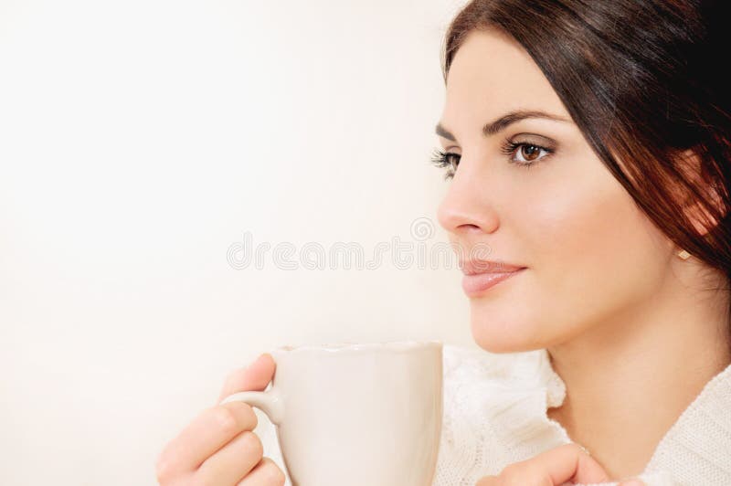 Young woman with long hair and brown eyes drinking coffee or tea from a cup