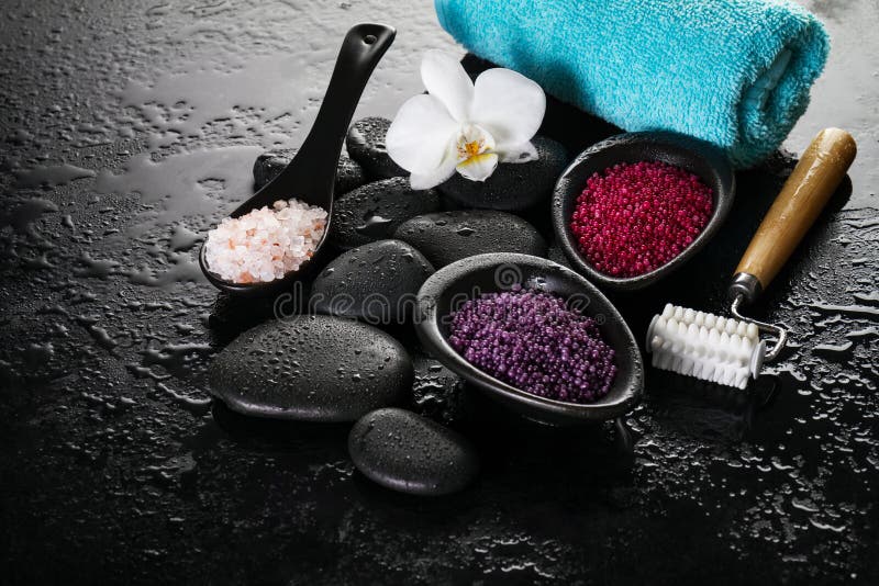 Beautiful Spa Set Spa Products with Essential Oils, Soap, Towel, Spa Sea Salt on Dark Wet Background. Horizontal with Copy Space.