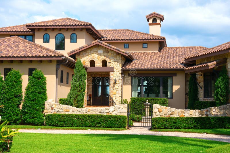 Beautiful Spanish style house exterior with natural rock facing and veneer siding