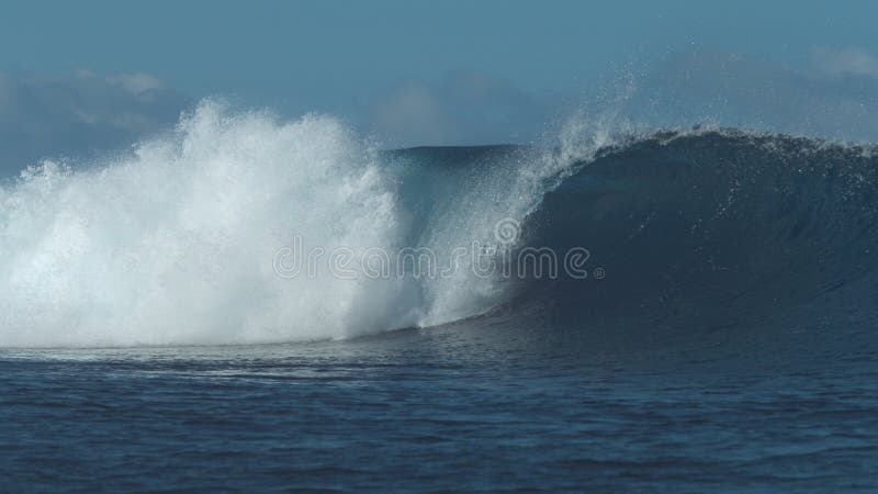 Beautiful sparkling ocean wave crashes wildly and sends blue water drops flying.