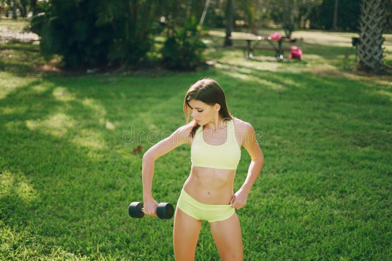 Young and beautiful girl athlete poses for photos holding a dumbbell. Young and beautiful girl athlete poses for photos holding a dumbbell