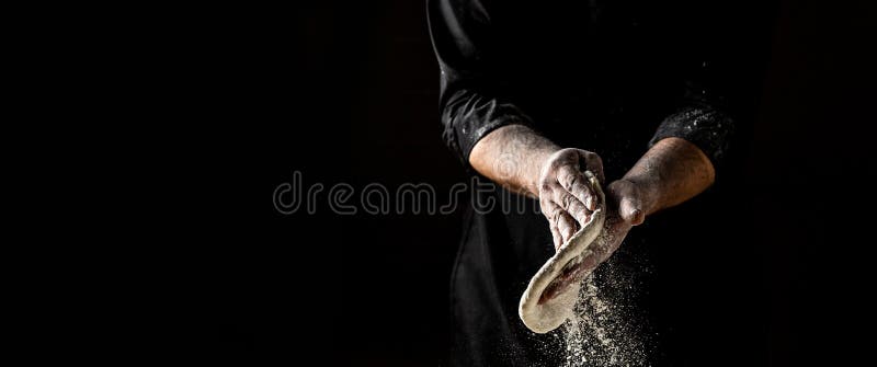 Beautiful and strong men`s hands knead the dough make bread, pasta or pizza. Powdery flour flying into air. chef hands with flour