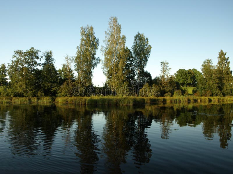 Beautiful summer landscape with calm lake, reflections of different trees