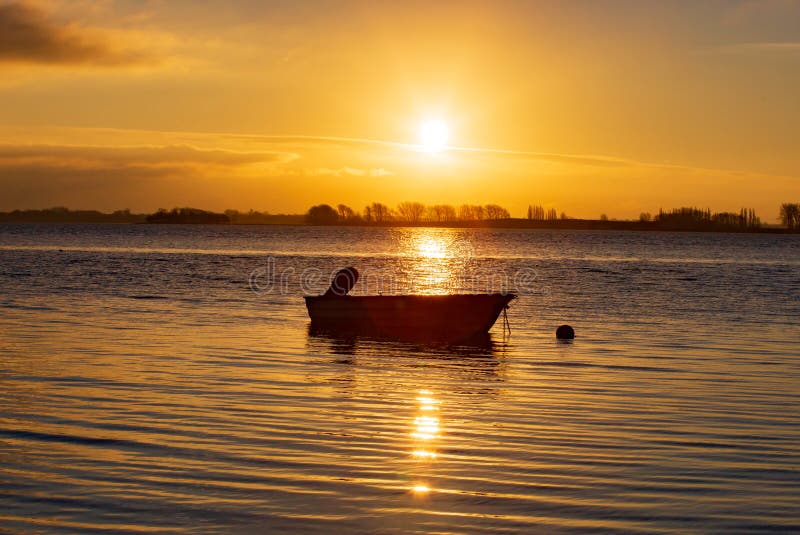 Beautiful sunrise over the sea with a small boat in the sun`s rays