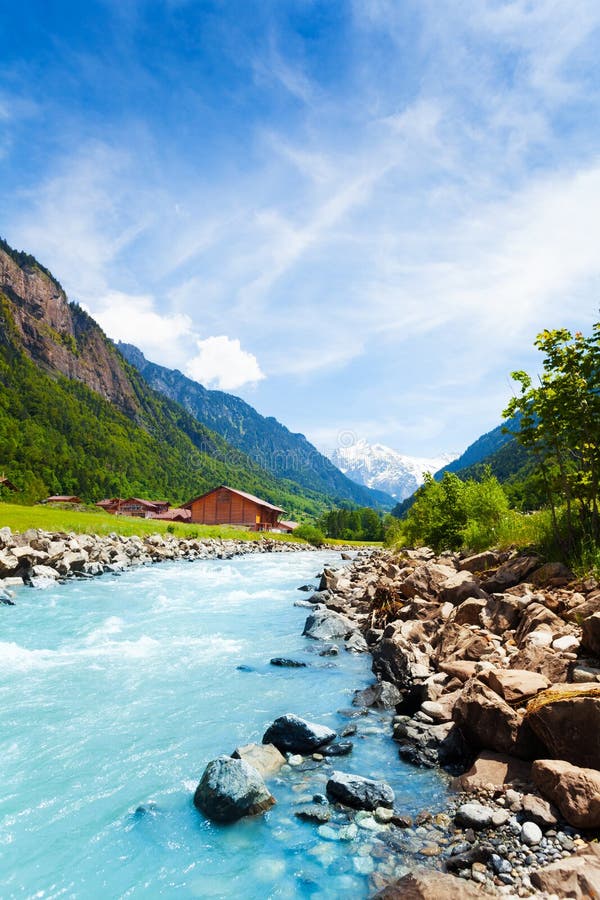 Beautiful Swiss landscape with river stream. Rocks, blue sky and houses near Alps mountains in summer royalty free stock photos Beautiful Swiss landscape with river stream. Rocks, blue sky and houses near Alps mountains in summer royalty free stock photos