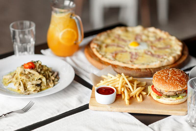 Beautiful table of italian pasta, pizza, burger and drinks. selective soft focus