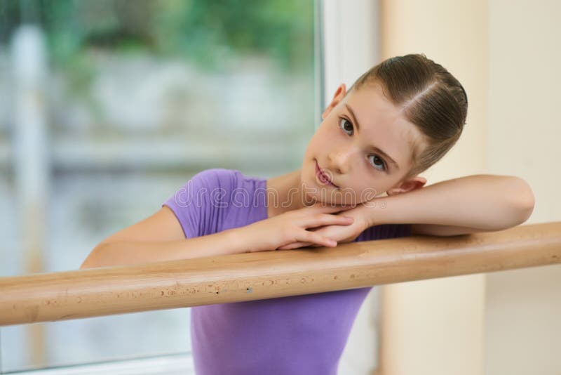 Beautiful teen ballerina resting on barre.