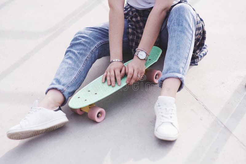 Beautiful teen female skater sitting on ramp at the skate park. Concept of summer urban activities stock photography Beautiful teen female skater sitting on ramp at the skate park. Concept of summer urban activities stock photography