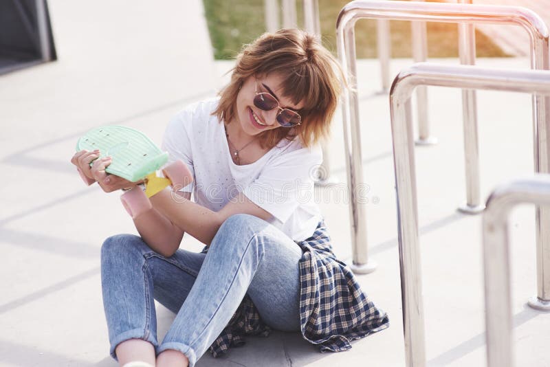 Beautiful teen female skater sitting on ramp at the skate park. Concept of summer urban activities royalty free stock photo Beautiful teen female skater sitting on ramp at the skate park. Concept of summer urban activities royalty free stock photo
