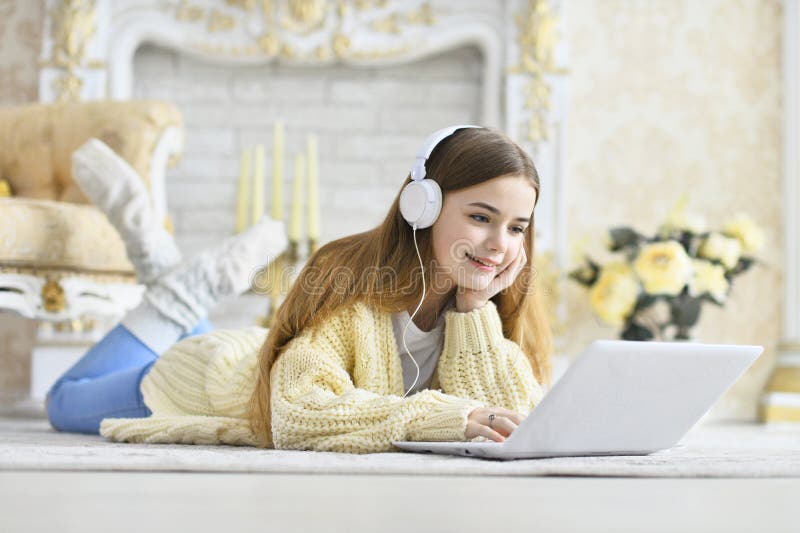 Beautiful teen girl lying on floor and using laptop