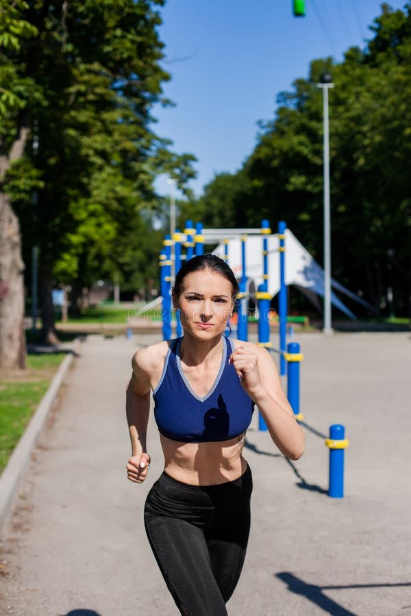 Young sportive teen in a bright blue sport bra and black leggings on the  sport playground. Photo of an athlete girl with a beautiful sports body  Stock Photo
