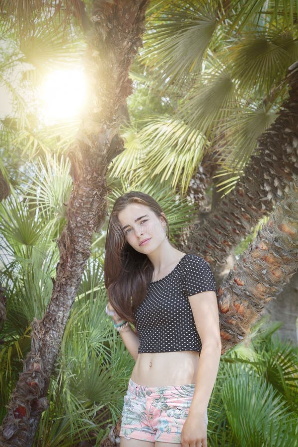 Beautiful teenage girl with palm trees and sun