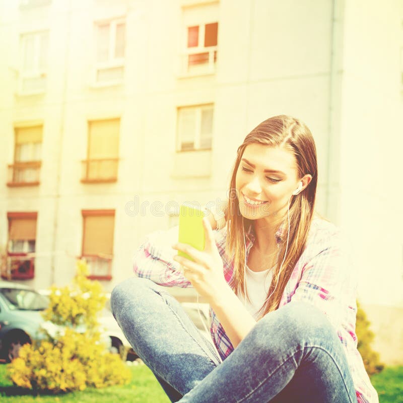 Beautiful teenage girl in park with smart phone listening to music stock photography Beautiful teenage girl in park with smart phone listening to music stock photography