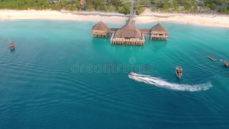 Beautiful thatch stilt house at Zanzibar Nungwi beach at evening time with blue Indian ocean aerial view