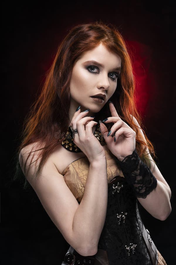 A beautiful thoughtful redhead cosplay girl wearing a Victorian-style steampunk dress and corset. Portrait. Black and red stock photography A beautiful thoughtful redhead cosplay girl wearing a Victorian-style steampunk dress and corset. Portrait. Black and red stock photography