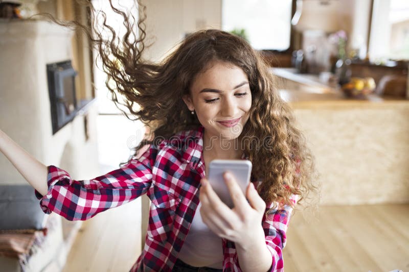 University student sitting at home on the floor scrolling on smartphone. stock photo