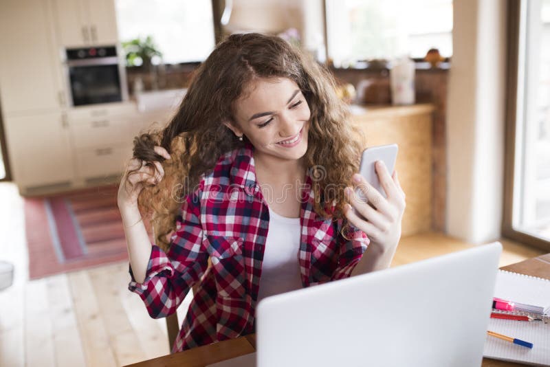 A beautiful university student is writing her thesis on a laptop, sitting at home on the couch. royalty free stock photos