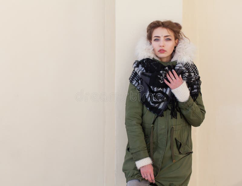 Beautiful unusual girl in a green jacket on background light wall stock photos