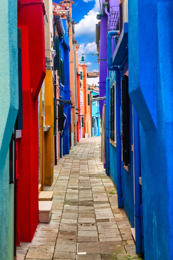 Beautiful vibrant colorful houses on Burano island with narrow cozy street near Venice in Italy stock photography