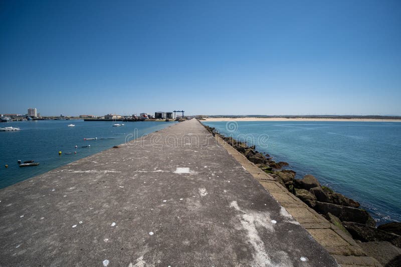 Beautiful view of breakwall and immense rock formations on coastline under clear blue sky stock photography