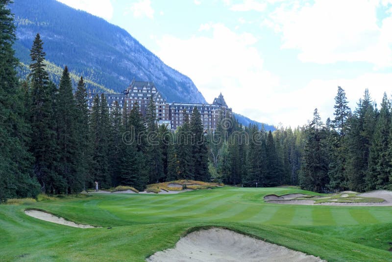 A beautiful view of a par 4 golf hole on a course with a huge mountain in the background, surrounded by forest