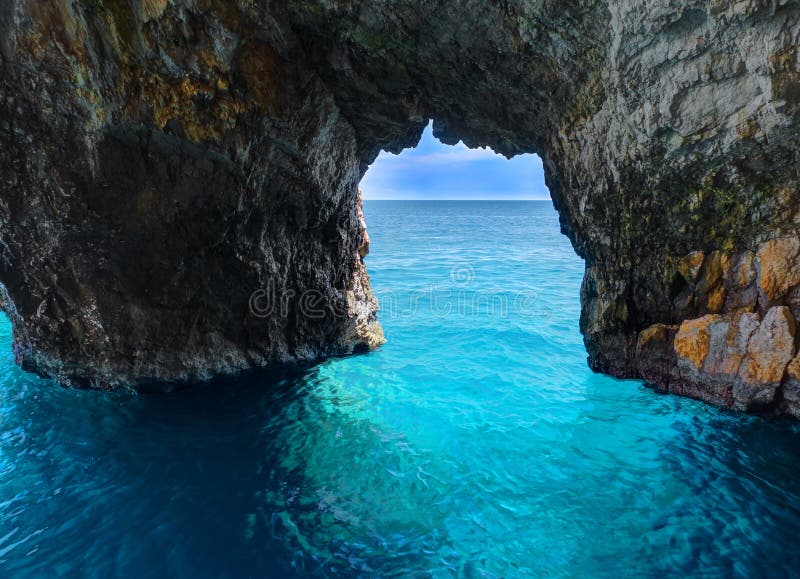 Beautiful view on rock arces arches of Blue caves from sightseeing boat with tourists in blue water of Ionian Sea inside cave, Isl