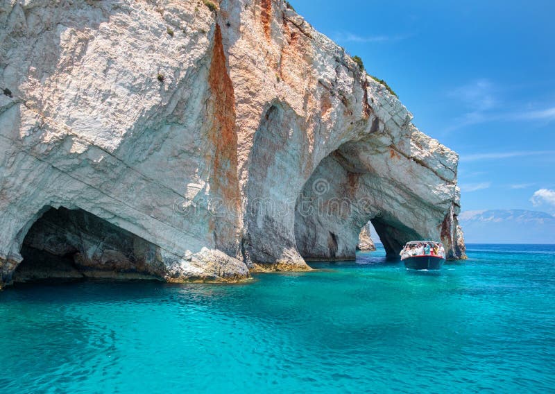 Beautiful view on rock arces arches of Blue caves and travel sightseeing boat with tourists in blue water. Famous Greece holidays vacations sightseeing tours