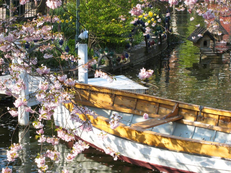 Beautiful view of a wooden boat surrounded by a sea of ​​flowers in a small lake - in Tivoli in Copenhagen in Denmark. Beautiful view of a wooden boat surrounded by a sea of ​​flowers in a small lake - in Tivoli in Copenhagen in Denmark