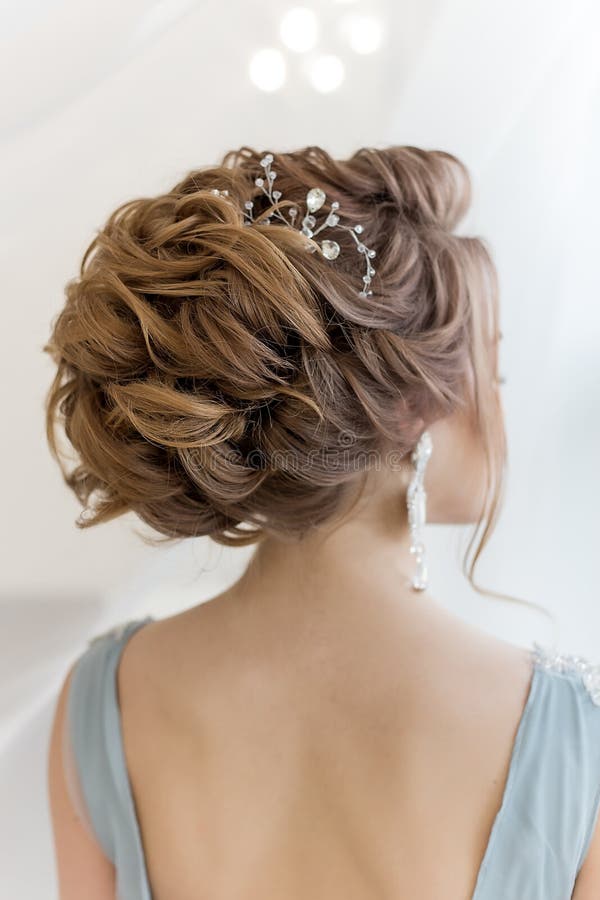 Beautiful volume hairstyle for a bride in a gentle blue light dress with large earrings and adornment in hair stock images Beautiful volume hairstyle for a bride in a gentle blue light dress with large earrings and adornment in hair stock images