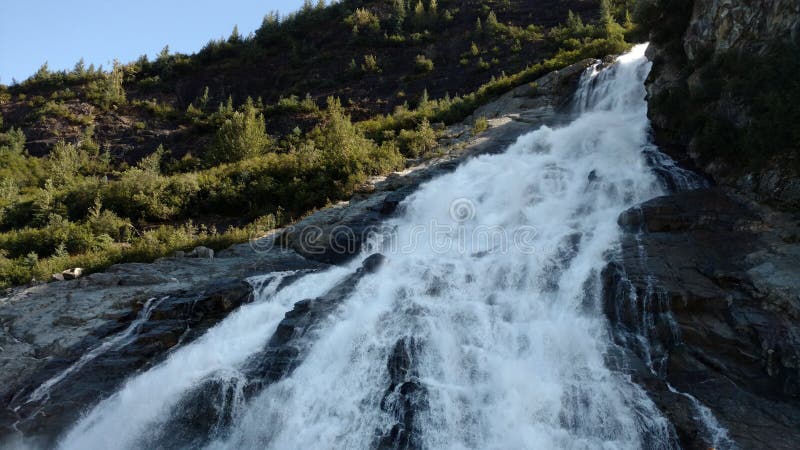 Beautiful Waterfall along side Mendenhall Glacier in Juneau Alaska. Large Glacier sliding into a lake with a waterfall beside it. Very popular tourist stop royalty free stock photo Beautiful Waterfall along side Mendenhall Glacier in Juneau Alaska. Large Glacier sliding into a lake with a waterfall beside it. Very popular tourist stop royalty free stock photo