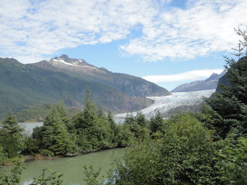 Beautiful Waterfall along side Mendenhall Glacier in Juneau Alaska. Large Glacier sliding into a lake with a waterfall beside it. Very popular tourist stop stock photography Beautiful Waterfall along side Mendenhall Glacier in Juneau Alaska. Large Glacier sliding into a lake with a waterfall beside it. Very popular tourist stop stock photography
