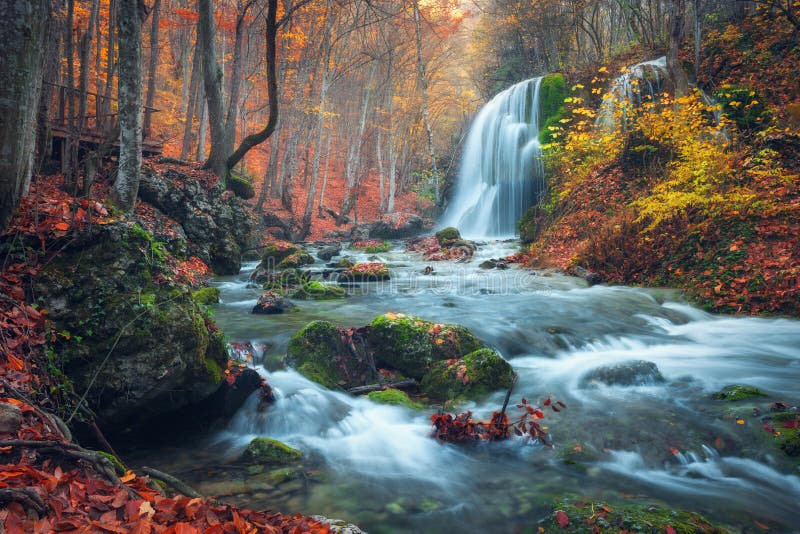 Bellissimo cascata autunno foresta montagne sul tramonto.