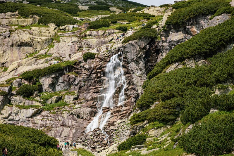 Krásny vodopád s vodným prúdom padajúcim z hory so zelenými kríkmi.