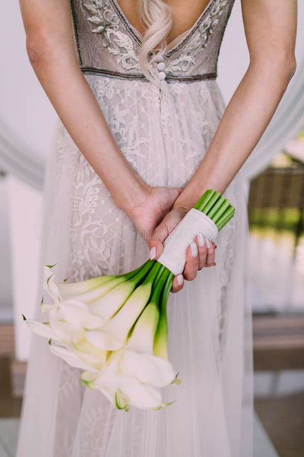 Beautiful wedding bouquet of calla flowers in hands of the bride. Artwork. Soft focus on a bouquet. Back, detail.