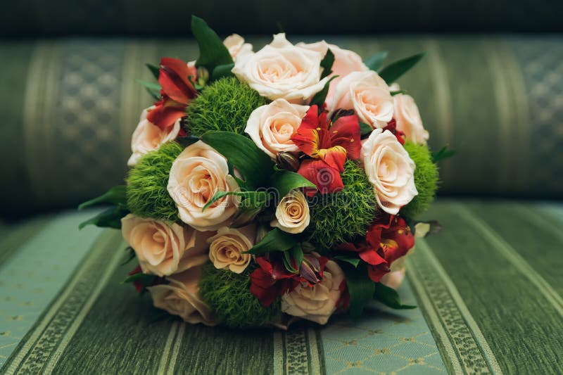 Beautiful wedding bouquet of roses lying on sofa