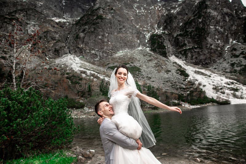 Beautiful wedding photosession. The groom circles his young bride, on the shore of the lake Morskie Oko. Poland stock photography Beautiful wedding photosession. The groom circles his young bride, on the shore of the lake Morskie Oko. Poland stock photography