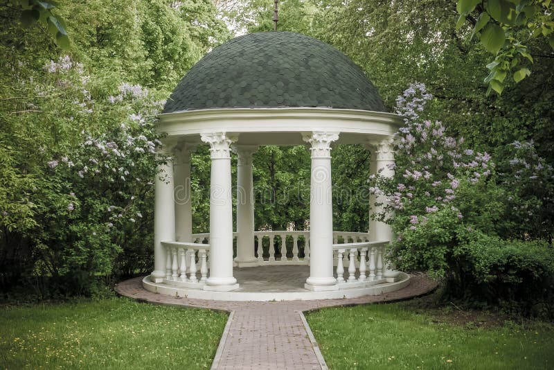 Beautiful white gazebo in a blooming spring Park