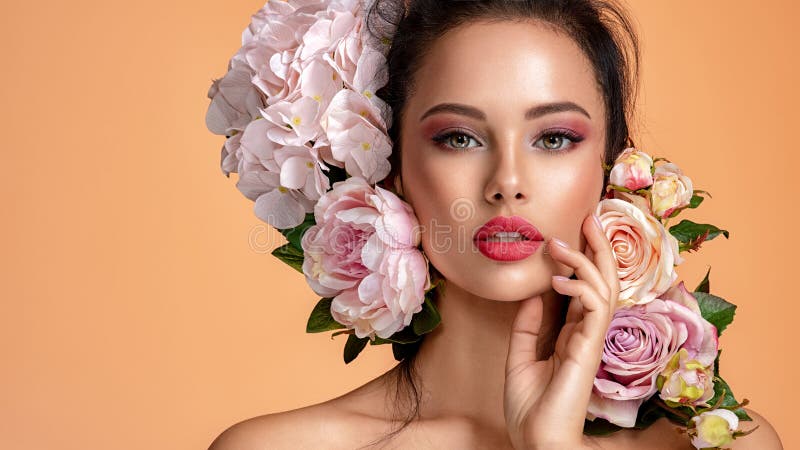 Beautiful white girl with flowers. Stunning brunette girl with big bouquet flowers of roses. Closeup face of young beautiful woman