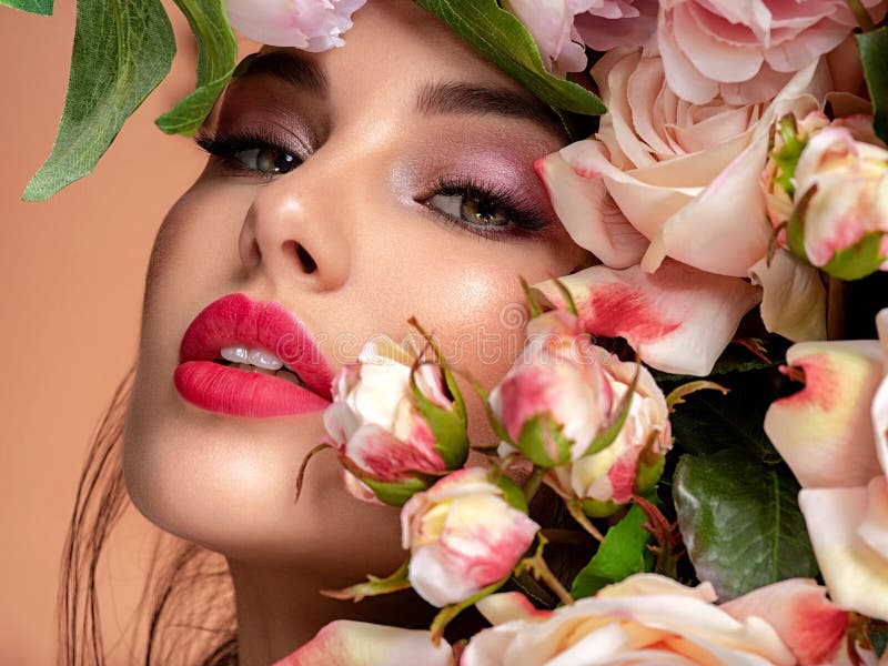 Beautiful white girl with flowers. Stunning brunette girl with big bouquet flowers of roses. Closeup face of young beautiful woman