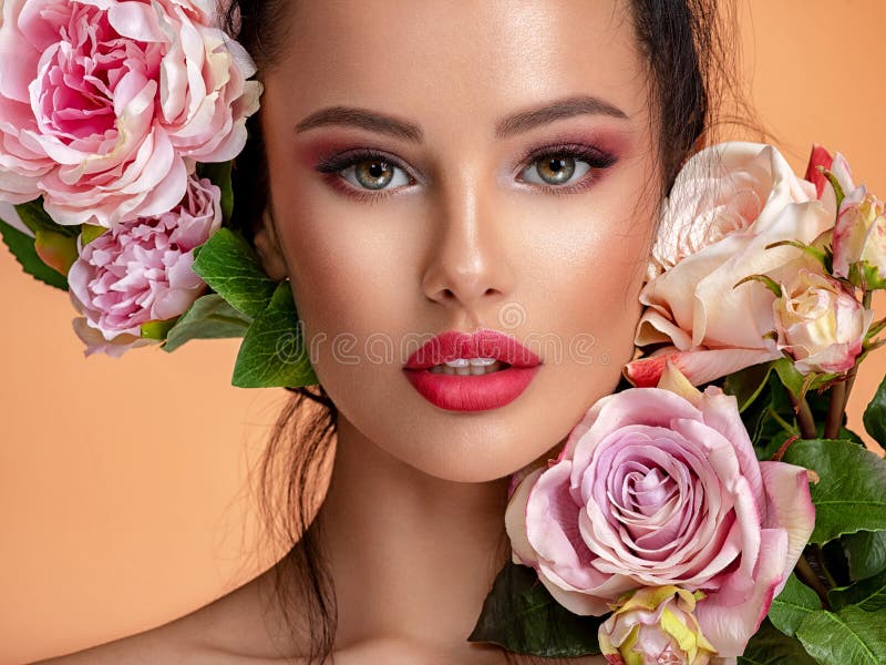 Beautiful white girl with flowers. Stunning brunette girl with big bouquet flowers of roses. Closeup face of young beautiful woman